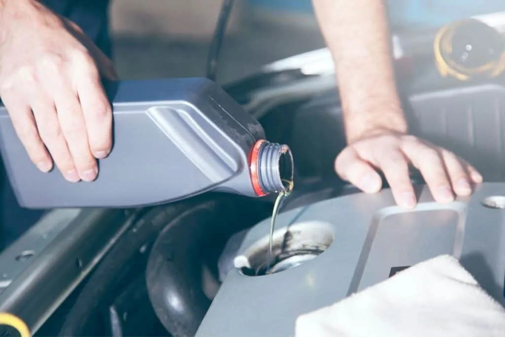 man filling up oil in car