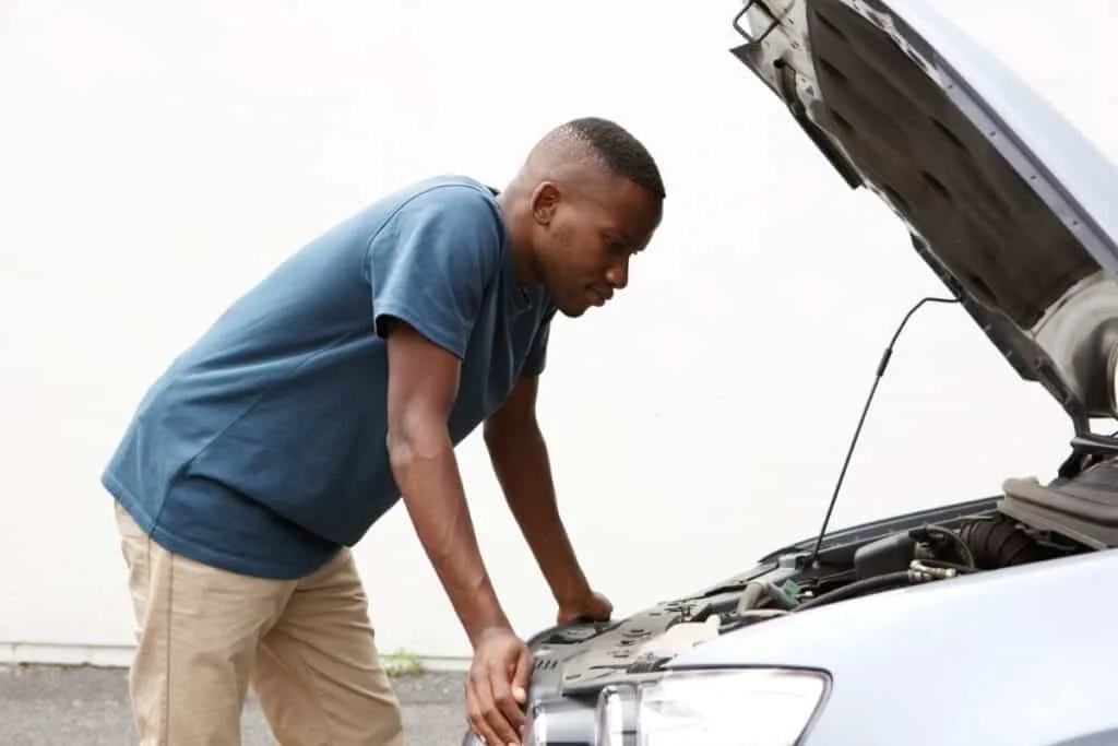 man checking under hood of car