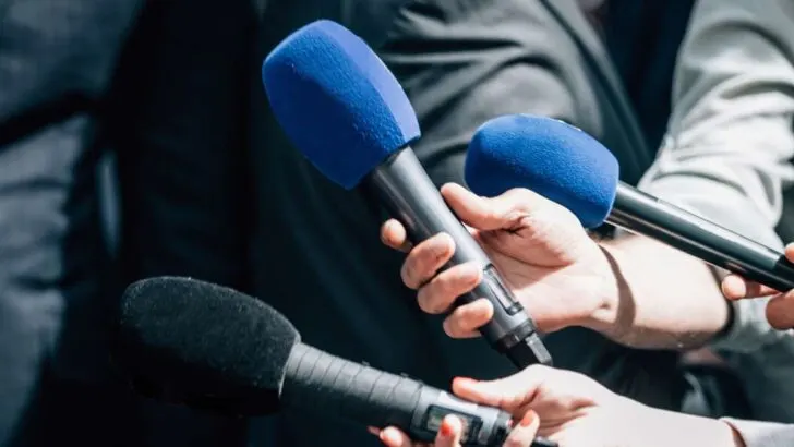 reporters holding microphones taking an official statement